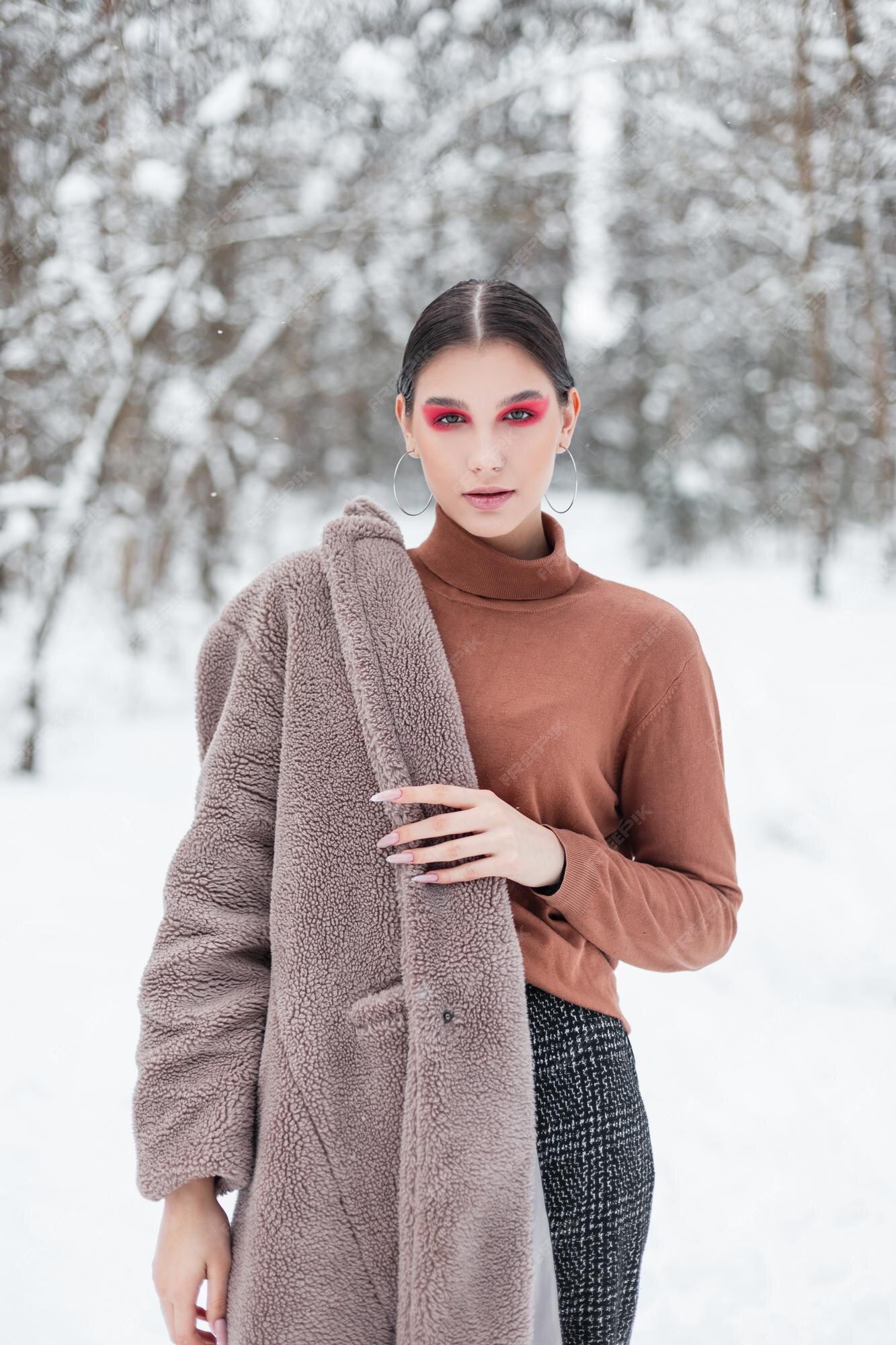 Bastante joven con maquillaje de color rosa en ropa de invierno de moda con suéter vintage y abrigo en un parque nevado | Foto Premium Bastante joven con maquillaje de color rosa en ropa de invierno de moda con suéter vintage y abrigo en un parque nevado | Foto Premium