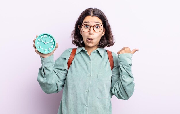 Bastante joven mirando asombrado con incredulidad. concepto de reloj despertador