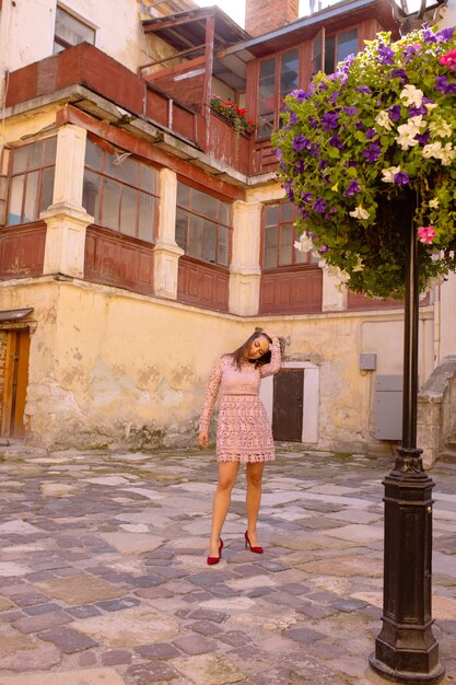 Bastante joven modelo con un vestido de moda, posando junto a la cama de flores en el patio