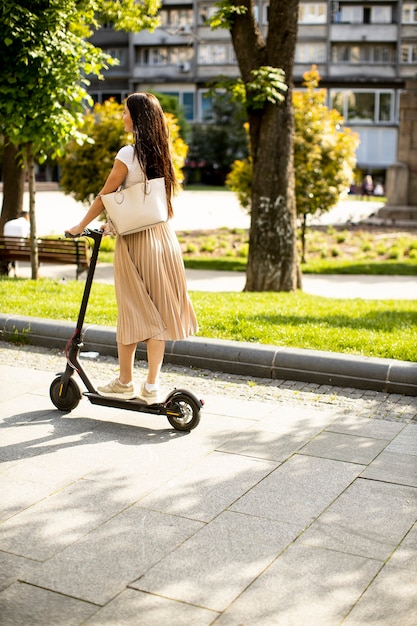 Bastante joven montando un scooter eléctrico en una calle