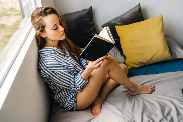 Bastante joven mujer caucásica sosteniendo un libro en sus manos mientras mira a la cámara