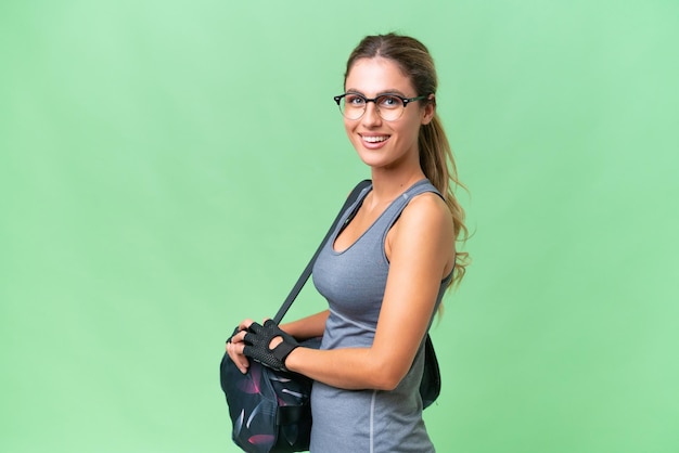 Bastante joven mujer deportiva uruguaya con bolsa deportiva sobre fondo aislado sonriendo mucho