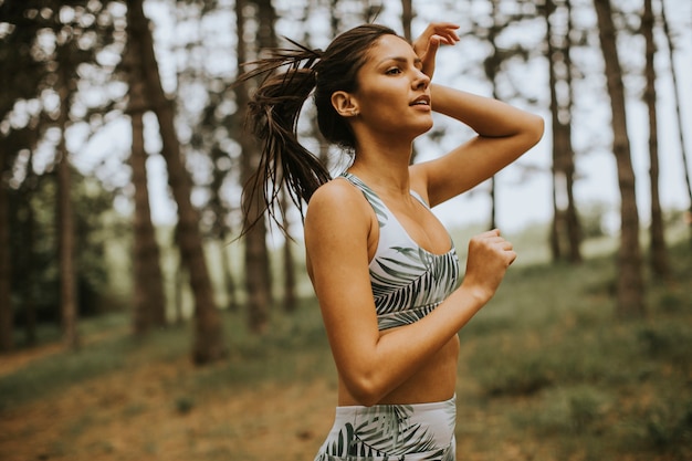 Bastante joven mujer fitness corriendo en el sendero del bosque