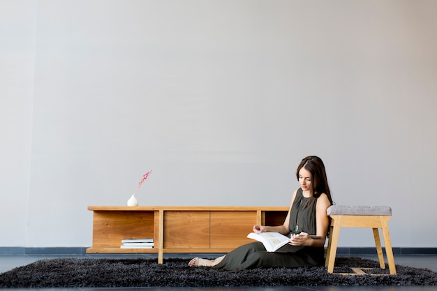 Bastante joven mujer leyendo un libro en la habitación moderna