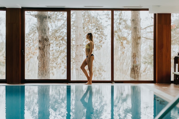 Bastante joven mujer de pie junto a la piscina