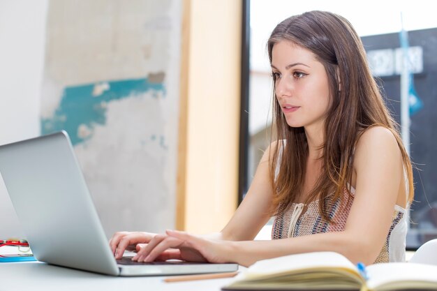 Bastante joven mujer que trabaja en la computadora portátil en la oficina