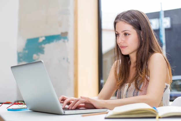 Bastante joven mujer que trabaja en la computadora portátil en la oficina