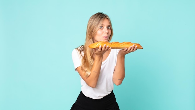 Bastante joven mujer rubia sosteniendo una baguette de pan