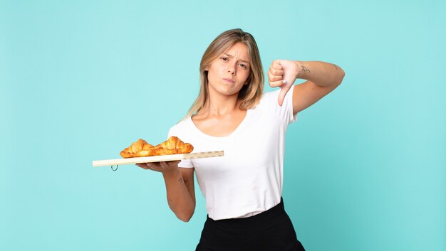 Bastante joven mujer rubia sosteniendo una bandeja de croissant