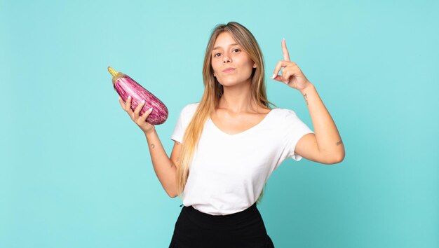 Bastante joven mujer rubia sosteniendo una berenjena