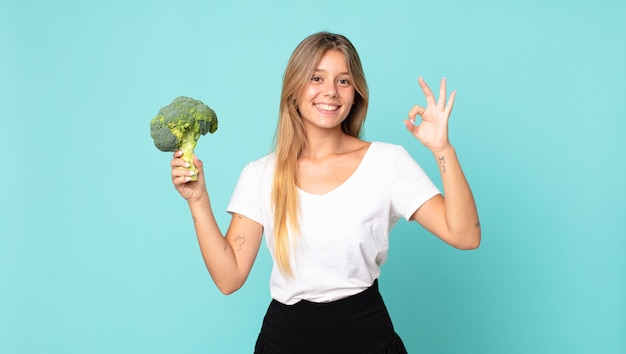 Foto bastante joven mujer rubia sosteniendo un brócoli
