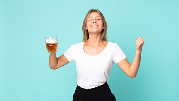 Bastante joven mujer rubia sosteniendo una pinta de cerveza