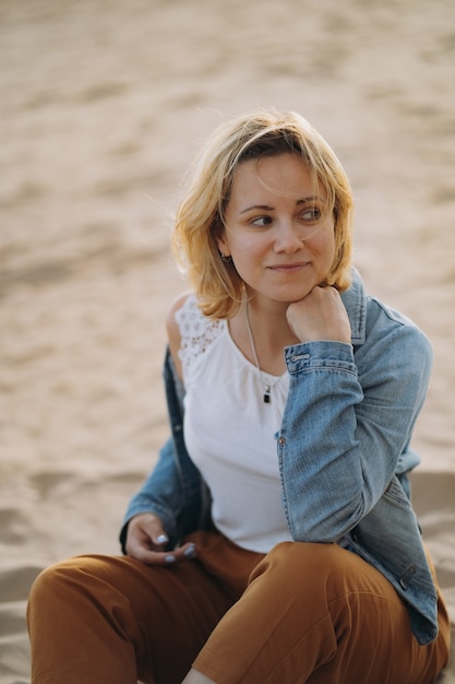 Bastante joven mujer sonriente caucásica disfrutando del sol en la playa al atardecer