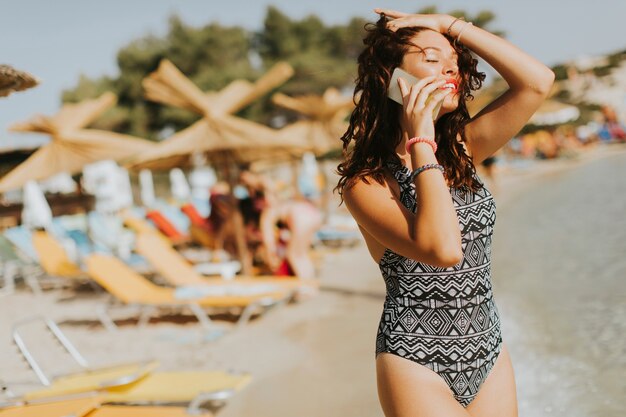 Foto bastante joven mujer con teléfono móvil en la playa