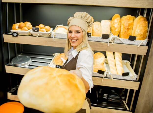 Bastante joven mujer vendiendo pan fresco en la panadería