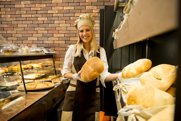 Bastante joven mujer vendiendo pan fresco en la panadería