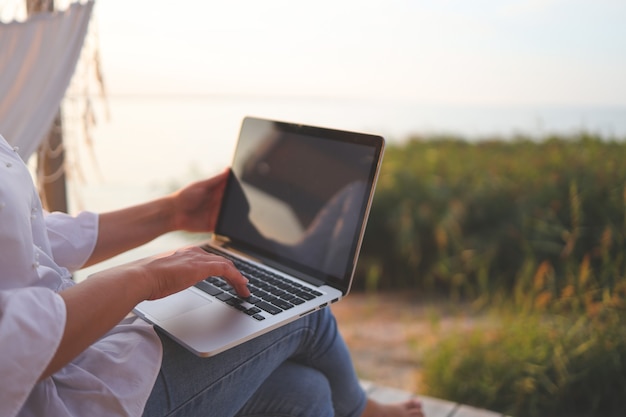 Bastante joven navegando por internet en un portátil al aire libre