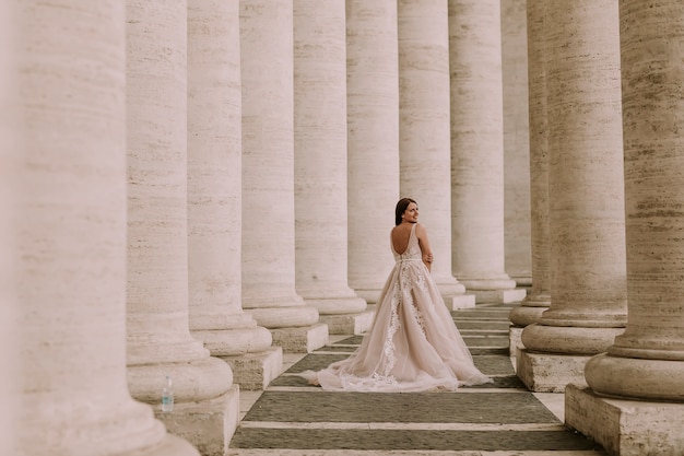 Bastante joven novia en vestido de novia en la columnata del Vaticano