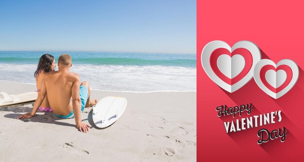 Foto bastante joven pareja con sus tablas de surf mirando al mar contra el feliz día de san valentín