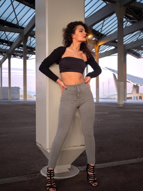 Bastante joven con el pelo rizado posando en la calle. Mujer elegante y atractiva. Estilo urbano