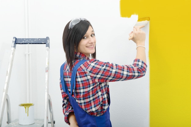 Bastante joven pinta la pared de color amarillo