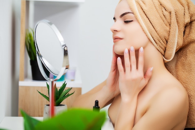 Bastante joven pone maquillaje en la cara en el baño.