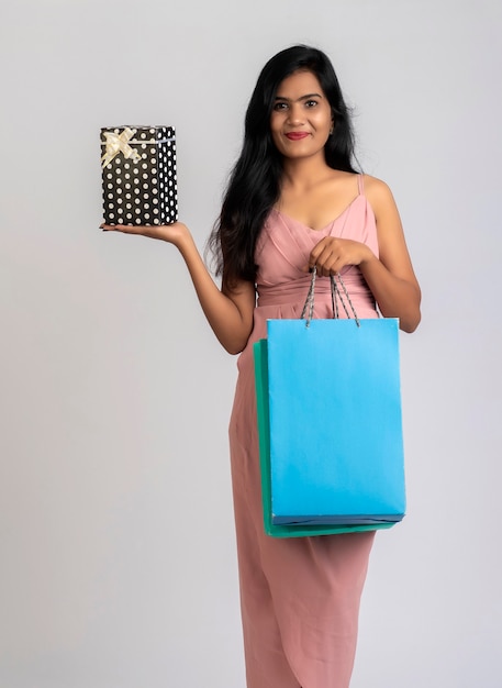 Bastante joven posando con bolsa de compras y caja de regalo