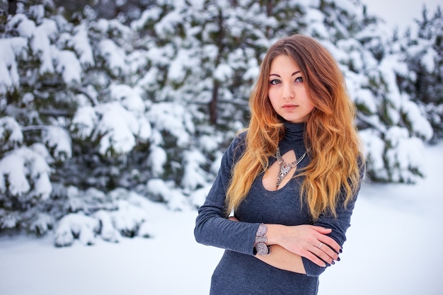 Bastante joven posando en el invierno en el bosque frío con pinos.