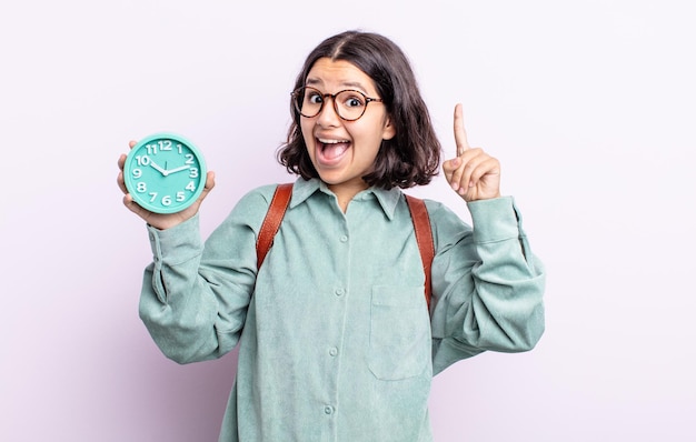 Foto bastante joven que se siente como un genio feliz y emocionado después de realizar una idea. concepto de reloj despertador