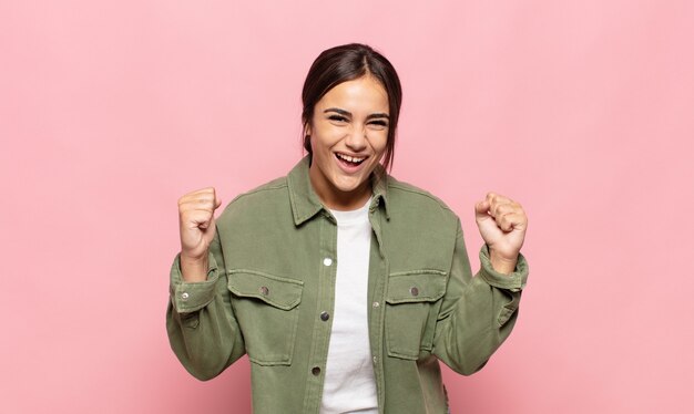 Bastante joven que se siente sorprendida, emocionada y feliz, riendo y celebrando el éxito, diciendo ¡guau!