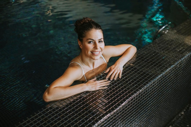 Bastante joven relajándose junto a la piscina de la piscina cubierta