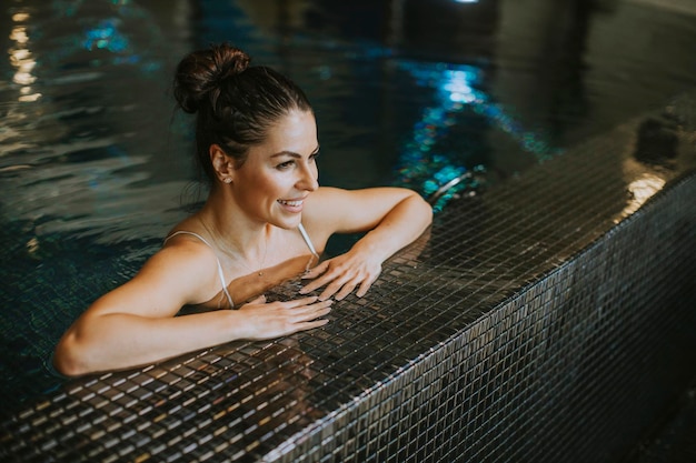 Bastante joven relajándose junto a la piscina de la piscina cubierta