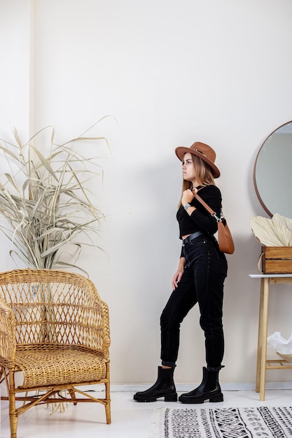 Bastante joven en ropa de moda con jeans negros y zapatos de moda. Hermosas piernas femeninas en botas de cuero