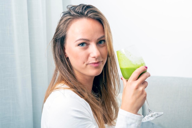 Bastante joven rubia con un vaso de batido de espinacas concepto de salud vegetariano