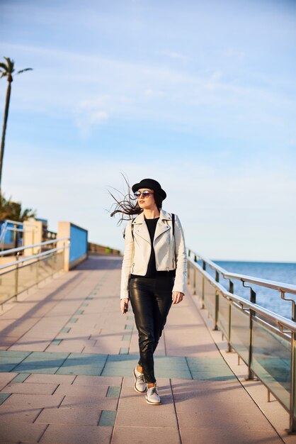 Bastante joven con sombrero negro caminando por el mar