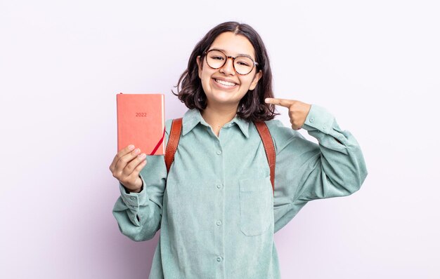 Bastante joven sonriendo con confianza apuntando a su propia amplia sonrisa. Concepto de agenda 2022