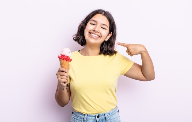 Bastante joven sonriendo con confianza apuntando a su propia amplia sonrisa. concepto de helado