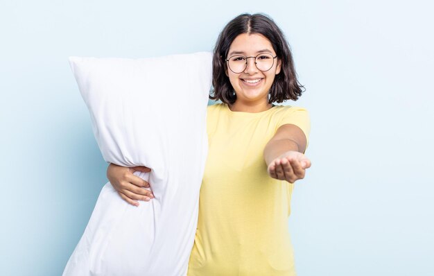 Bastante joven sonriendo felizmente con amigable y ofreciendo y mostrando un concepto. concepto de cama