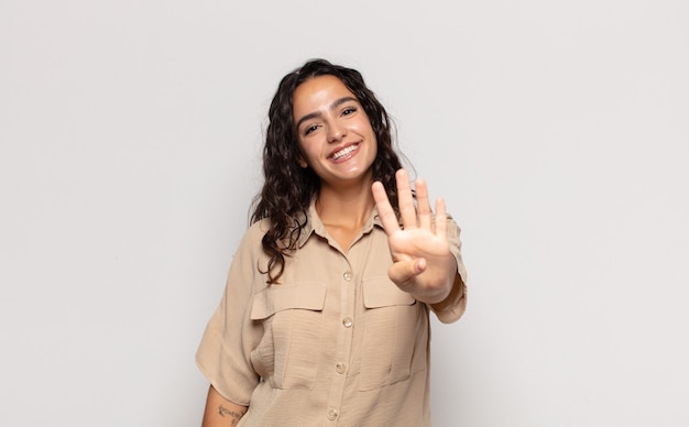 Bastante joven sonriendo y mirando amistosamente, mostrando el número cuatro o cuarto con la mano hacia adelante, contando hacia atrás