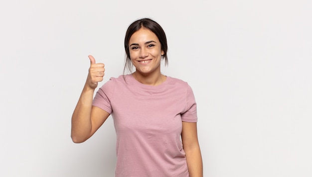 Bastante joven sonriendo y mirando amistosamente, mostrando el número uno o el primero con la mano hacia adelante, contando hacia atrás