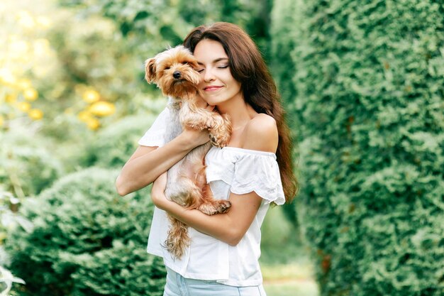 Foto bastante joven sonriente sosteniendo pequeño perro cachorro yorkshire terrier