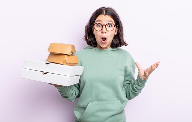 Bastante joven sorprendida sorprendida y asombrada con un increíble concepto sorpresa de comida rápida para llevar