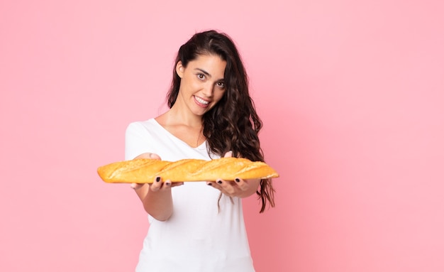 Bastante joven sosteniendo una baguette de pan