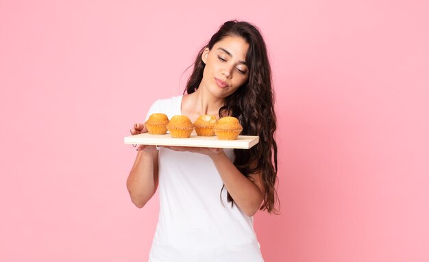 Bastante joven sosteniendo una bandeja de muffins