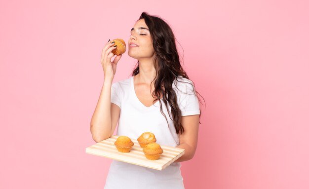 Bastante joven sosteniendo una bandeja de muffins