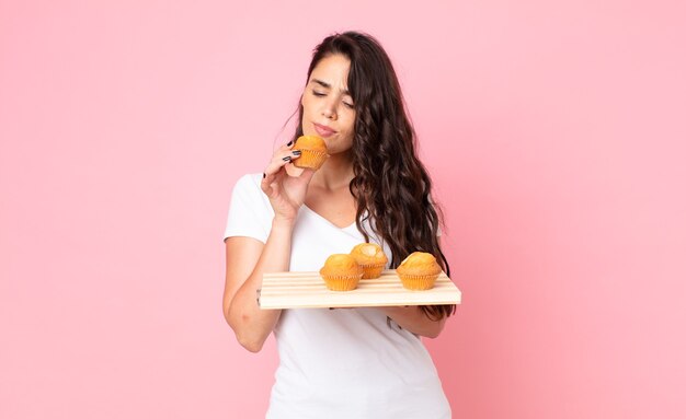 Bastante joven sosteniendo una bandeja de muffins