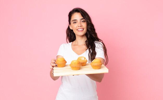 Bastante joven sosteniendo una bandeja de muffins