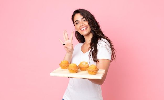 Bastante joven sosteniendo una bandeja de muffins