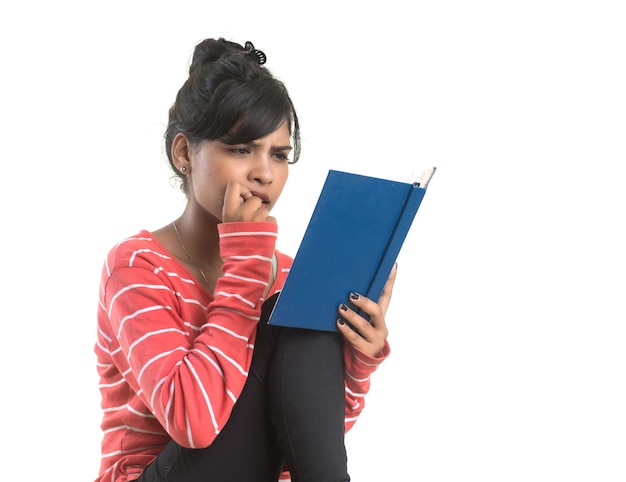 Bastante joven sosteniendo el libro y posando en la pared blanca