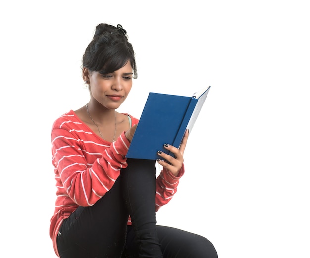 Bastante joven sosteniendo el libro y posando en la pared blanca